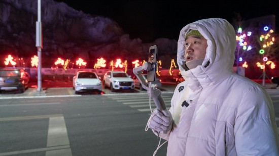 在吉林市阿什哈達霧凇觀景帶，霧凇播報員正在直播。新華社記者 李典 攝